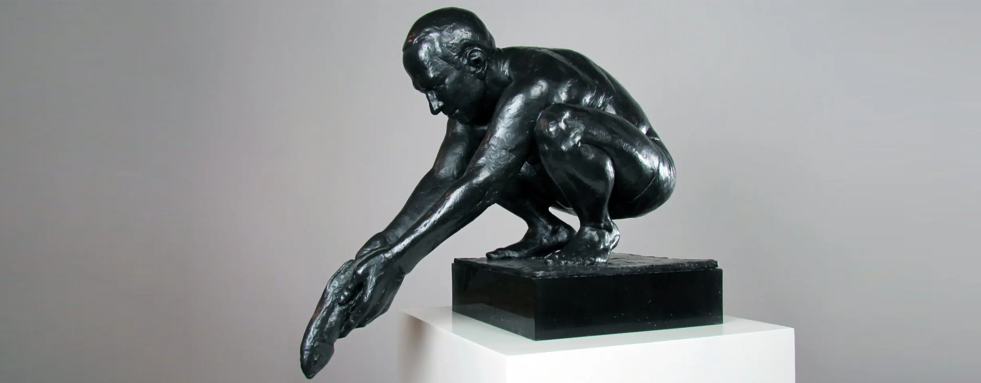 A sculpture of a man sitting on top of a black object.