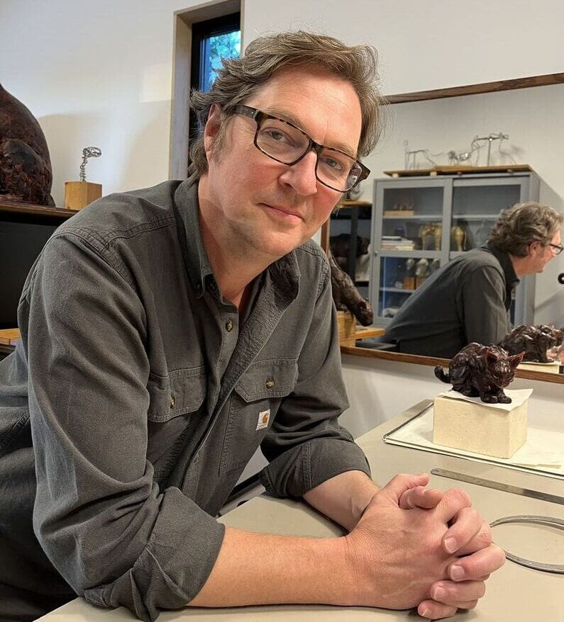 A man sitting at a table with his hands crossed.